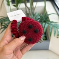 Detail van een rode pluche haarelastiek met zwarte stippen en fluwelen textuur op hand - Rode Bes Koekje Pluche Haarelastiekje