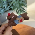 Close-up of a cute brown corduroy teddy bear hair clip featuring cherry and heart bag details - Laying Brown Dog Duckbill Clip