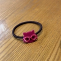 Detailansicht eines magentafarbenen Katzen-Haargummis mit Marmormuster auf einer Holzfläche - Rosé Pink Katze Haargummi