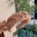 Detail van kameelbruine gebreide hoofdband met woltextuur en een gedraaide knoop - Bruin