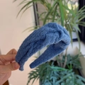 Detailopname van de blauwe gebreide hoofdband met een dikke kabelpatroon en textuur - Donkerblauw