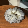 Detailansicht eines cremefarbenen Spitzen-Scrunchies mit eleganten schwarzen Wellenkanten - Weiß Mehrlagig Mit Schwarzem Rand