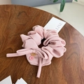 Detaillierte Makroansicht von rosa Chiffon-Haargummi mit Bändern und Knöpfen auf Holz - Rosa Einfarbig Schleife Scrunchie