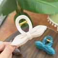 Close-up of elegant bow-shaped hair claws in cream, teal, and brown colors - White Calico