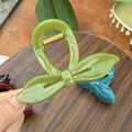 Detail view of large grass green resin hair claw clip with bow leaf design and gold spring - Seedling Green