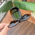 Detail of amber resin bow hair claw clip with glossy finish and metal spring - Glossy Light Tortoise
