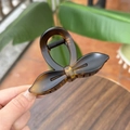 Close-up of elegant bow-shaped hair claw clip with amber and black gradient resin finish - Matte Light Tortoise