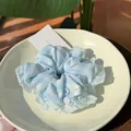 Blau gestreifter Haargummi mit Knöpfen und Rüschenkante auf einer Keramikschale - Blau-weiß gestreift