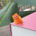 Gros plan d'une mini pince à cheveux hibou orange en acétate sur un livre rose et vert - Mini Hibou Orange