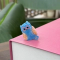 Détail d'une mini pince à cheveux hibou en acétate bleu marbré sur un livre rose - Mini Hibou Bleu