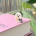 Macro d'une petite barrette hibou en acétate avec finition nacrée et détails dorés brillants - Texture Blanche Style Souriant