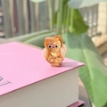Vue détaillée d'une pince à cheveux chouette en acétate orange sur un livre rose - Doré (Hibou à Nœud)