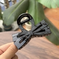 Détail d'une pince à cheveux élégante avec double nœud noir sur une table en bois - Pince à Nœud Double Couche / 8cm / Noir Brillant