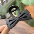 Vue détaillée d'une pince à cheveux à double nœud noir mat tenue à la main dehors - Pince à Nœud Double Couche / 8cm / Noir mat
