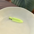 Close-up of neon green jelly hair clip on a ceramic dish with natural leaf background - Neon Yellow
