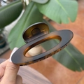 Detail view of tortoiseshell amber hair claw clip held by hand against garden background - 10cm / Matte Light Tortoise