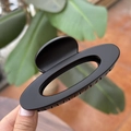 Close-up of a 10cm matte black hollow oval hair claw clip held in hand outdoors - 10cm / Matte Black