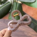 Macro view of marbled tortoise shell hair claw clip with heart cut-outs and bow shape - Transparent Brown