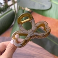Detailed close-up of amber brown bow hair claw clip with golden metal spring mechanism - Jelly Yellow Green