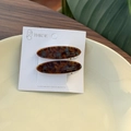 Close-up of two acetate tortoise shell hair clips on a white display card in a ceramic dish - Tortoiseshell