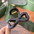 Detail view of brown bow hair claw clip with crocodile skin texture and gold spring - Chocolate