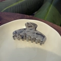 Elegante pinza de pelo de acetato jaspeado con siete dientes en un plato de cerámica - Mármol Gris Blanco - Garra de Siete Dientes