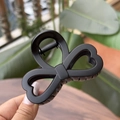 Detail of matte black heart-shaped hair claw clip with bow-knot design and metal spring - Matte Black