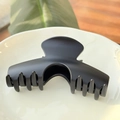 Détail d'une grande pince à cheveux arquée noire mate sur un plateau en céramique - Arche Carrée XL Boucle Papillon / Noir mat