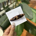 Détail d'une barrette ovale en acétate écaille de tortue avec gravure sur carte support - Pince Bec de Canard Ovale Étiquette Dorée / Écaille Léopard