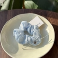 Nahaufnahme von blauem Karo-Haargummi mit silberner Schleife und Bärenanhänger auf Teller - Blau Karo Silber Schleife Haargummi