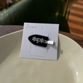 Gros plan sur la barrette fleur noire avec strass verts et roses sur assiette céramique - Noir - Fleur Strass Pince à Bec de Canard