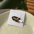Gros plan d'une pince à cheveux fleur en acétate avec strass vert sur plat céramique - Écaille de Tortue - Fleur Strass Pince à Bec de Canard