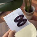 Détail de barrettes ovales en acétate violet foncé avec lettrage doré sur carte blanche - Grains De Café - Pince Ovale En Forme De Canard