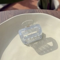 Close-up of a transparent light blue square hair claw clip with a gold metal spring - Ice Blue