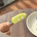Dettaglio di una dolce molletta gialla con cinque fiori bianchi 3D e perline dorate - Uva Verde