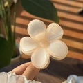 Detail of a creamy jelly flower hair claw clip held in hand with soft natural sunlight - White Petal Orange Edge Clear Flower Claw