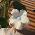 Close-up of a translucent blue and cream jelly floral hair claw clip in natural sunlight - White Petal Blue Edge Solid Color Flower Claw