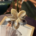 Dettaglio ravvicinato della pinza per capelli a fiore marmorizzato con eleganti texture - Sfumatura Caramello Acero