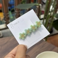Detail einer hellgrünen Acetat-Blumen-Haarspange mit goldener Mitte auf weißer Karte - Hellgrün