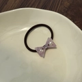 Detail of lavender bow hair tie with pearls and crystals on a white ceramic plate - Sakura Pink
