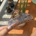 Primer plano de pinza para el pelo de acrílico ámbar con resorte dorado bajo el sol - Ámbar transparente