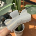 Gros plan d'une grande pince à cheveux blanc crème pailletée dorée à la lumière naturelle - Pince Papillon Cœur Pailleté / Gris
