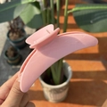 Detail of pink crescent moon hair claw clip held in natural outdoor sunlight - Sakura Pink