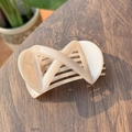 Elegante pinza per capelli beige a forma di X con finitura lucida su fondo di legno - Rosa Nude Chiaro