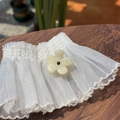 Nahaufnahme weißer Organza-Manschetten mit Stickerei und floralen Knopf-Applikationen - Hellgelb