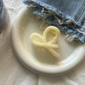 Close-up of cream-colored twist hair claw clip on porcelain plate with denim backdrop - Creamy Yellow Ribbon Claw Medium