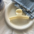 Gros plan d'une pince à cheveux en résine crème placée sur un plateau en céramique blanc - Jaune Crème Barre Ronde Pince Grande