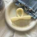 Gros plan d'une pince à cheveux crème en forme de nœud avec ressort doré sur plateau - Jaune Crème Barre Nœud Grande