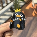 Close-up of a black glitter penguin hair claw with yellow crown and pearl details - Crown Pearl Penguin