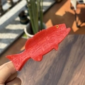 Detail of a red fish claw clip made of acetic acid with marbled texture in outdoor light - Red Fish